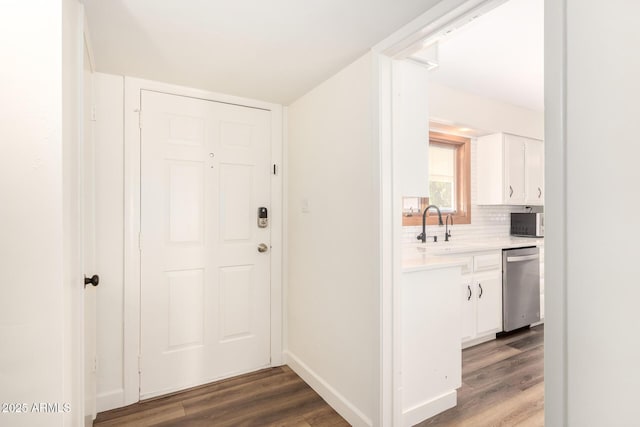 interior space with a sink, baseboards, and wood finished floors