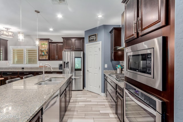 10738 W Rowel Rd, Peoria, AZ 85383 - kitchen featuring a sink, stainless steel appliances, dark brown cabinets, pendant lighting, and light stone countertops