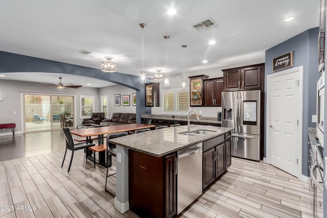 10738 W Rowel Rd, Peoria, AZ 85383 - kitchen featuring appliances with stainless steel finishes, a sink, arched walkways, wood finish floors, and dark brown cabinetry