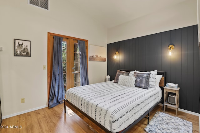 bedroom with wooden walls, vaulted ceiling, and hardwood / wood-style flooring