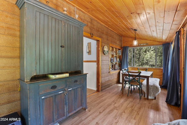 dining space with light hardwood / wood-style floors, vaulted ceiling, wooden ceiling, and wood walls