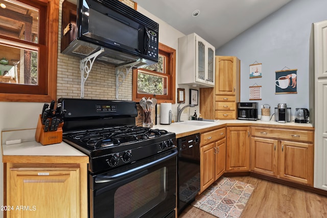 kitchen featuring black appliances, decorative backsplash, light hardwood / wood-style floors, and sink