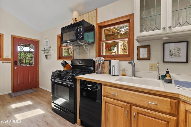 kitchen featuring sink, light hardwood / wood-style floors, lofted ceiling, and black appliances