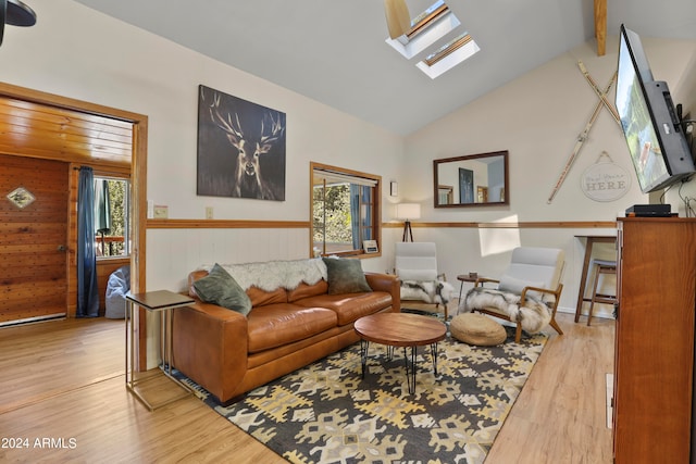 living room featuring plenty of natural light, light wood-type flooring, wooden walls, and a skylight