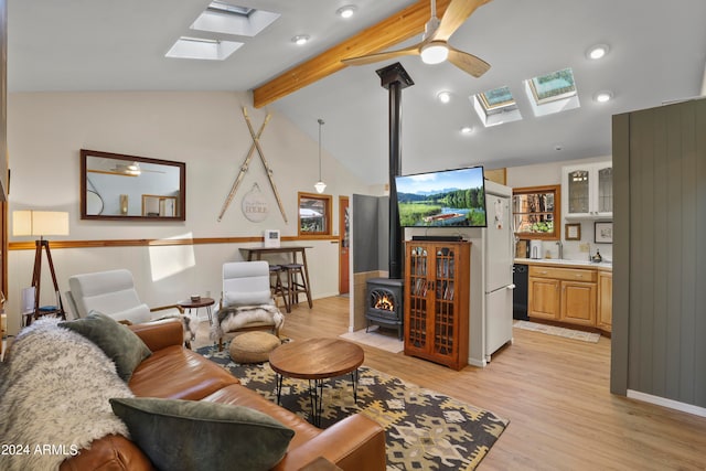 living room with lofted ceiling with beams, light hardwood / wood-style floors, a wood stove, and ceiling fan