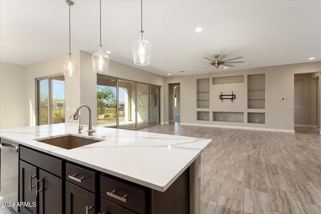 kitchen featuring built in shelves, dark brown cabinetry, ceiling fan, hanging light fixtures, and sink