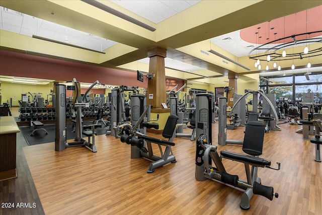 exercise room with decorative columns and hardwood / wood-style floors