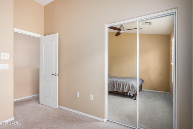 unfurnished bedroom with light colored carpet, a closet, and vaulted ceiling