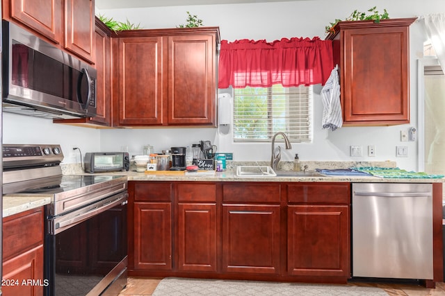 kitchen with light stone countertops, appliances with stainless steel finishes, and sink