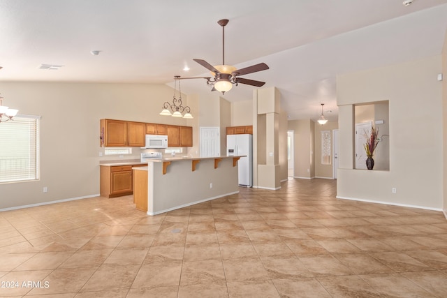 kitchen with ceiling fan with notable chandelier, high vaulted ceiling, a breakfast bar area, a center island, and white appliances