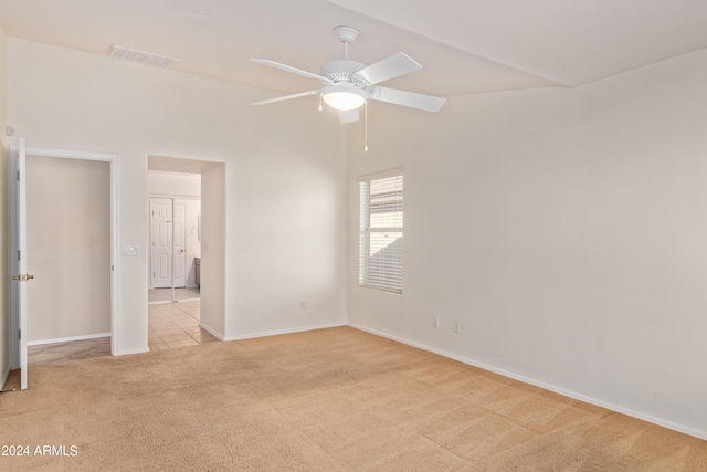 empty room featuring vaulted ceiling, light colored carpet, and ceiling fan