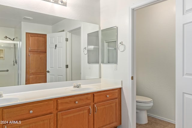 bathroom featuring a shower with door, vanity, tile patterned flooring, and toilet