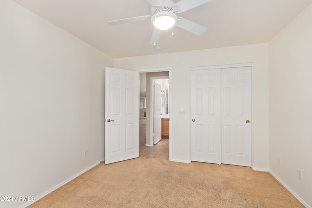 unfurnished bedroom with light colored carpet, ceiling fan, and a closet