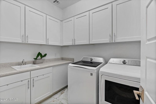 clothes washing area featuring washer and clothes dryer, cabinets, and sink