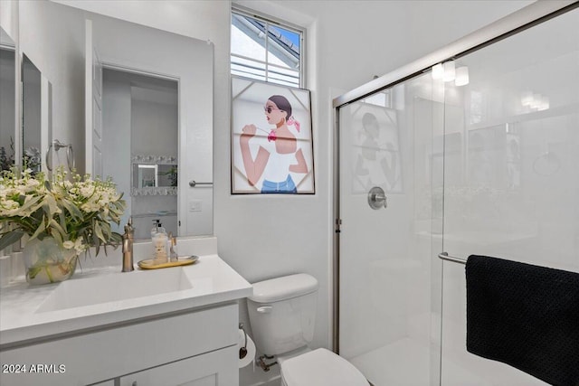 bathroom featuring vanity, toilet, and a shower with shower door