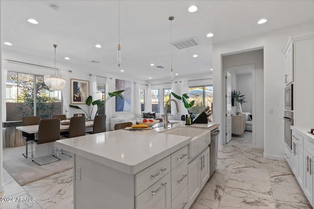 kitchen with pendant lighting, white cabinetry, and a kitchen island with sink