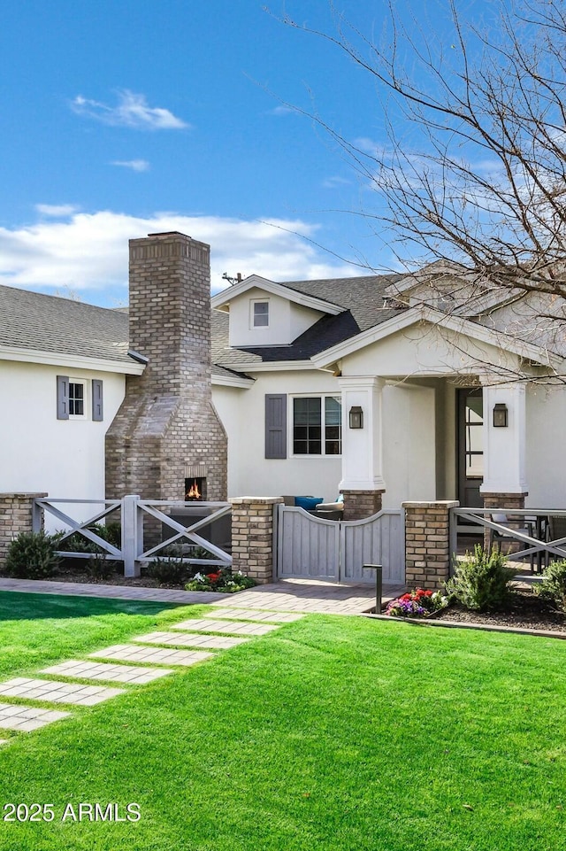 exterior space with a shingled roof, a yard, a chimney, and stucco siding