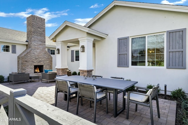 view of patio with outdoor dining space and an outdoor living space with a fireplace