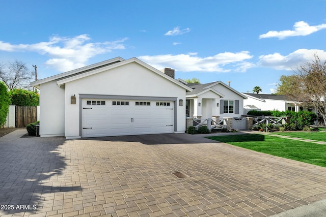 single story home with decorative driveway, a chimney, an attached garage, and stucco siding