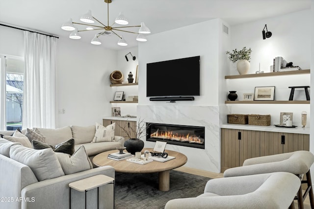 living area featuring a high end fireplace, visible vents, and a notable chandelier