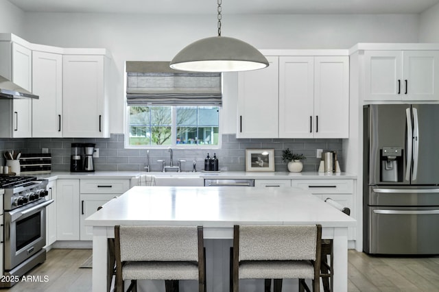 kitchen with a sink, a breakfast bar area, tasteful backsplash, and stainless steel appliances