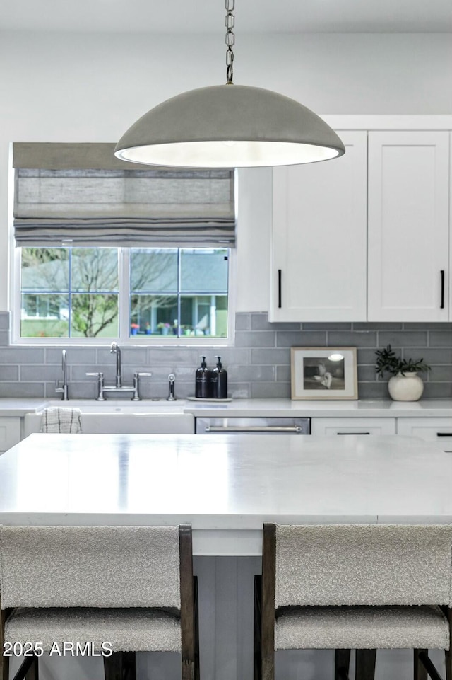 kitchen featuring light countertops, white cabinets, and backsplash