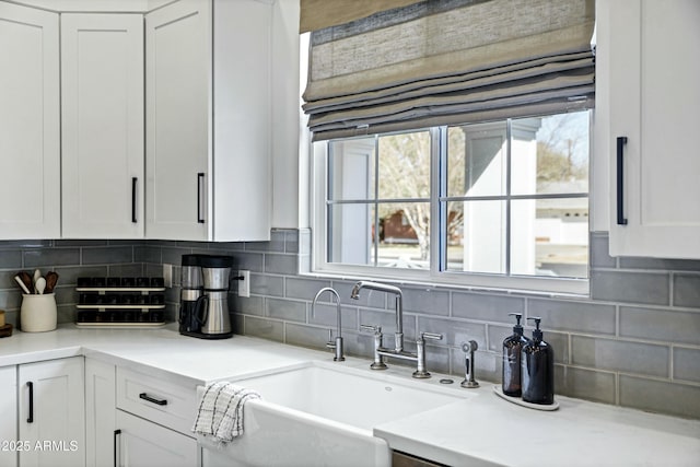 kitchen with a sink, decorative backsplash, white cabinets, and light countertops