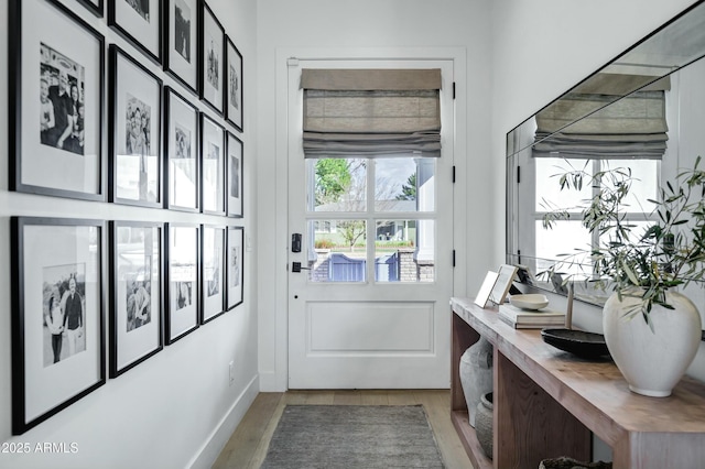 doorway featuring baseboards and wood finished floors