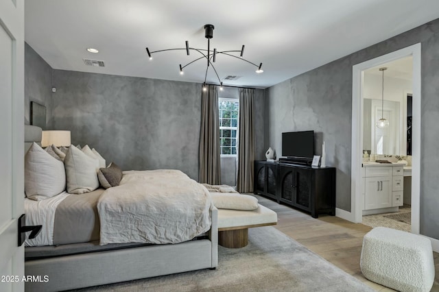 bedroom featuring connected bathroom, visible vents, light wood-style floors, and a chandelier