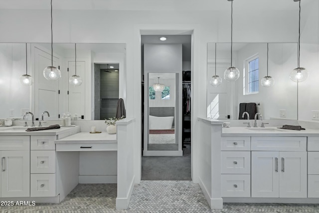 full bathroom with a spacious closet, two vanities, and a sink