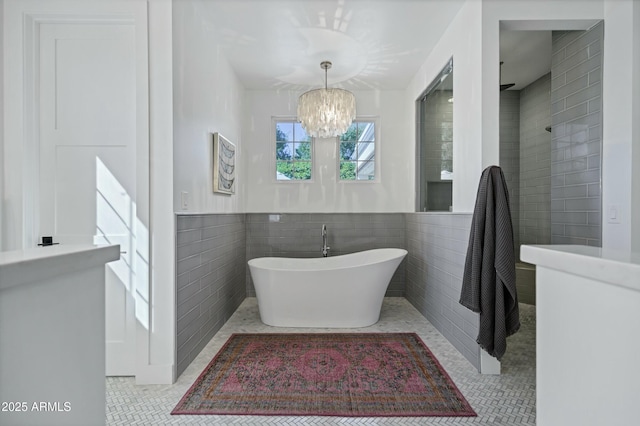 bathroom featuring tile patterned floors, a soaking tub, tile walls, and a chandelier