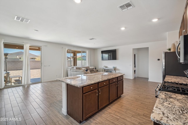 2335 W Sunland Ave, Phoenix, AZ 85041 - kitchen featuring appliances with stainless steel finishes, open floor plan, light wood-style floors, a kitchen island, and baseboards