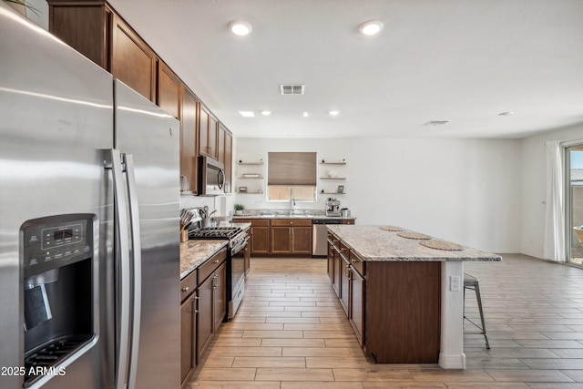 2335 W Sunland Ave, Phoenix, AZ 85041 - kitchen featuring appliances with stainless steel finishes, open shelves, a center island, a kitchen breakfast bar, and recessed lighting