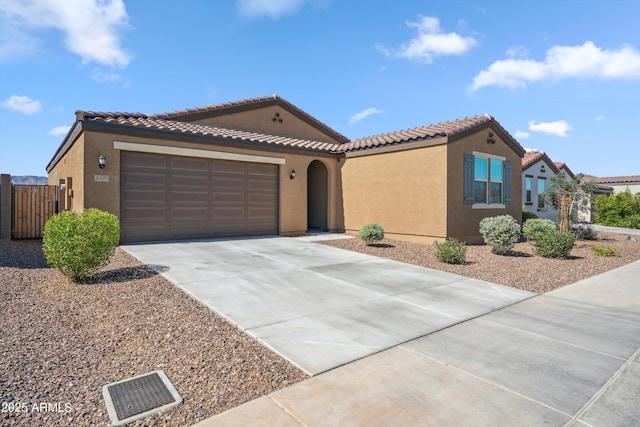 2335 W Sunland Ave, Phoenix, AZ 85041 - mediterranean / spanish house featuring a tile roof, concrete driveway, stucco siding, a garage, and a gate