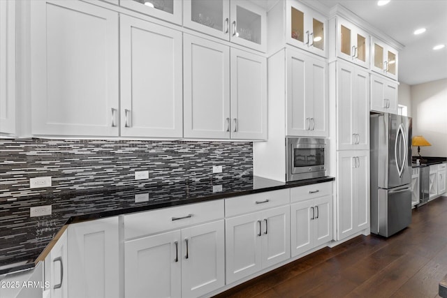 kitchen with tasteful backsplash, white cabinetry, stainless steel appliances, and dark wood-type flooring