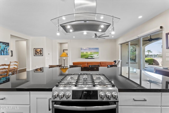 kitchen featuring white cabinets, stainless steel gas stove, ceiling fan, and island exhaust hood