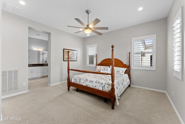 bedroom with multiple windows, ensuite bathroom, ceiling fan, and light colored carpet