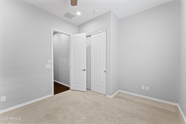 unfurnished bedroom with ceiling fan, light carpet, and a closet