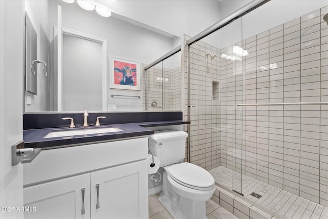 bathroom featuring tile patterned flooring, vanity, toilet, and an enclosed shower