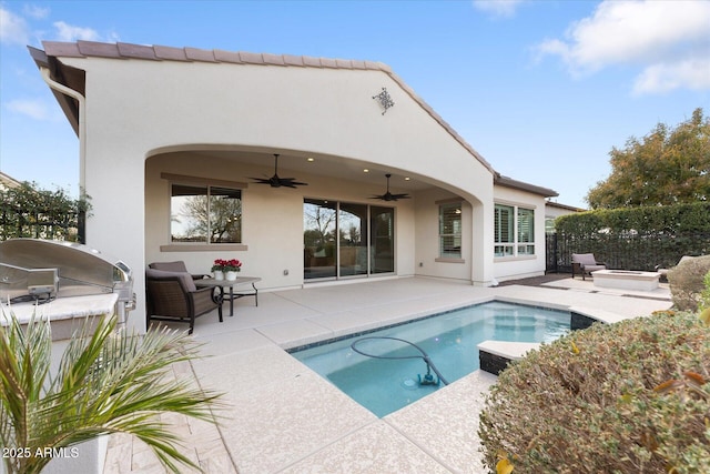 back of house with a fenced in pool, a patio area, ceiling fan, and an outdoor kitchen