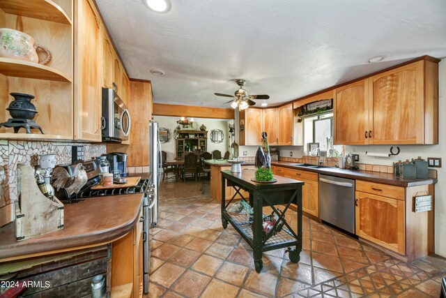 kitchen with a textured ceiling, ceiling fan, sink, and appliances with stainless steel finishes