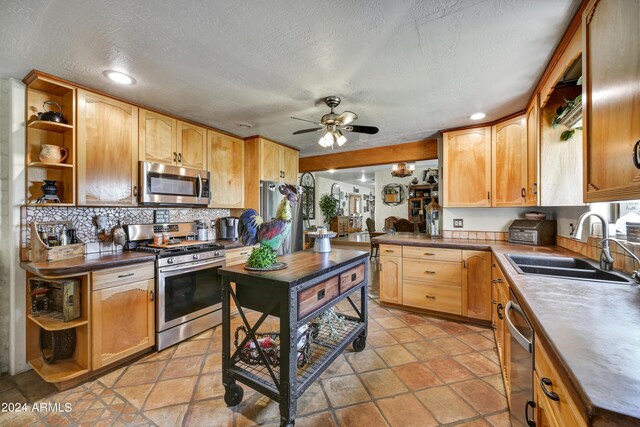 kitchen with a textured ceiling, stainless steel appliances, sink, ceiling fan, and decorative backsplash