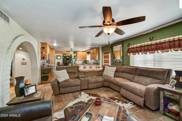 living room with ceiling fan and a textured ceiling