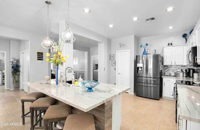 kitchen with a center island with sink, white cabinetry, light tile patterned floors, and stainless steel appliances