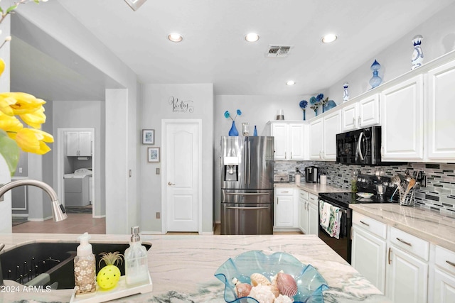 kitchen with sink, white cabinetry, black appliances, separate washer and dryer, and light stone countertops