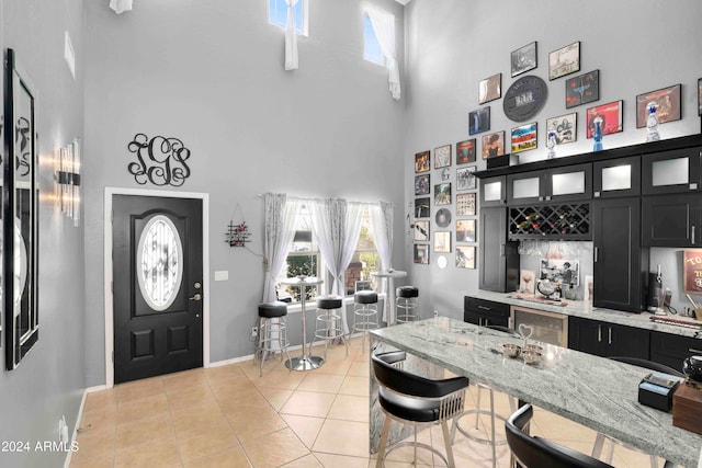 tiled entryway with a towering ceiling and indoor bar