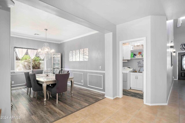 dining space with light hardwood / wood-style flooring, washer / clothes dryer, a notable chandelier, and ornamental molding