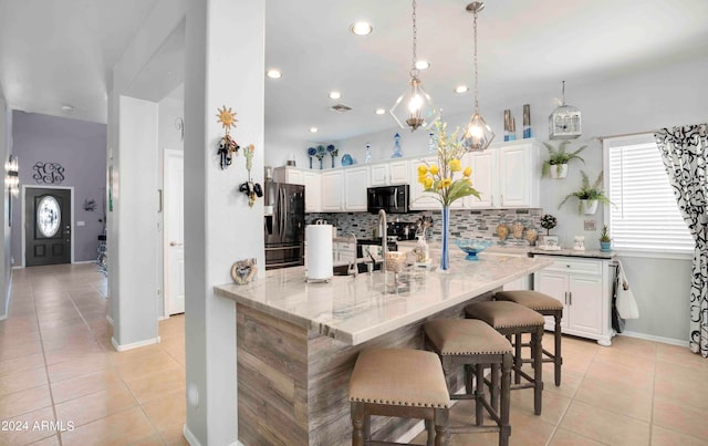 kitchen featuring a breakfast bar, light stone counters, white cabinetry, hanging light fixtures, and stainless steel appliances