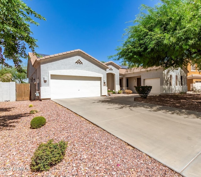 mediterranean / spanish house with driveway, stucco siding, an attached garage, and solar panels
