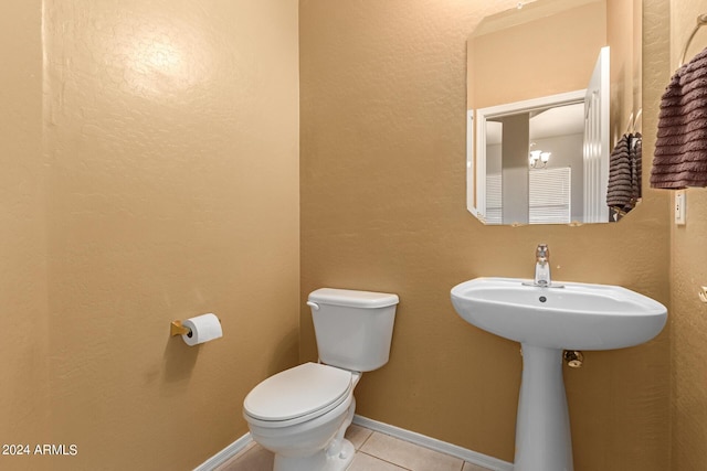 bathroom with toilet, an inviting chandelier, baseboards, and tile patterned flooring